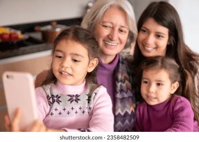 Detail of latin multigenerational family at tableengaged in fun activity, selfie. in kitchen home, indoors. Togetherness, multi-generation family, support concept. - Powered by Shutterstock