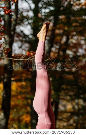 Detail of legs and feet of woman practicing yoga doing balance in the handstand pose in a forest.