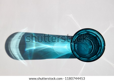 detail of light reflections of a blue waterglass in the sun on white background