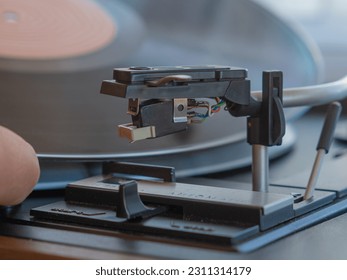 Detail of a male hand placing a black vinyl record on a vintage turntable - Shutterstock ID 2311314179