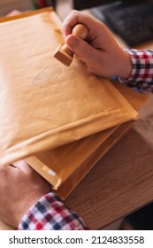 Detail Of Male Hand Putting Stamp On Envelope, Sending Mail; Small Business Owner Packing Products For Delivery; Entrepreneur Getting Online Store Orders Ready For Shipping