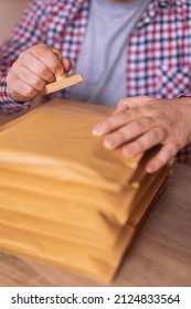 Detail Of Male Hand Putting Stamp On Envelope, Sending Mail; Small Business Owner Packing Products For Delivery; Entrepreneur Getting Online Store Orders Ready For Shipping