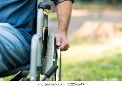 Detail of a man using a wheelchair in a park. Copy-space on the right side - Shutterstock ID 312242249