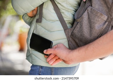 Detalle de la mano de un hombre robando un teléfono móvil del bolsillo de una chica