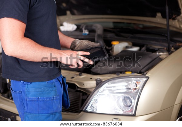 Detail of a mechanic with a digital tablet,\
car in background
