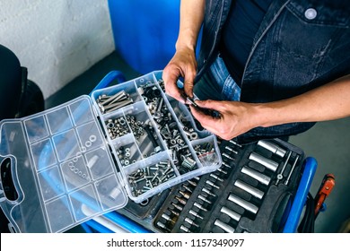 Detail of mechanic's hands choosing screws and nuts from a tool box in the workshop - Powered by Shutterstock