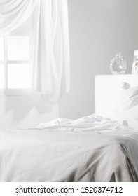 
Detail Of Messy Bedding In All White Bedroom With Window