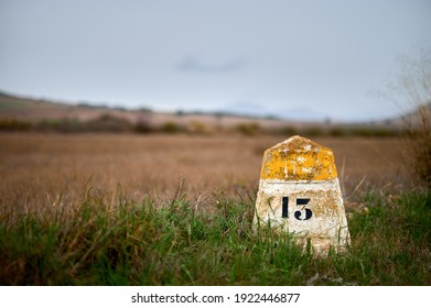 detail of a milestone or milepost sign on a rural road with hills in the background
