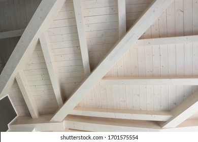 Detail of a modern wooden roof. All the beams are painted in a soft white