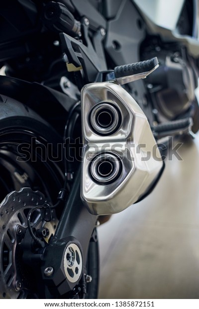 Detail of a\
motorcycle rear chain with exhaust pipes. Rear view of a motorcycle\
with the focus on chain.