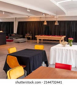 Detail Of A Multifunctional Space With Yellow Chairs And Tables In The Foreground, A Pool Table In The Background. Nobody Inside