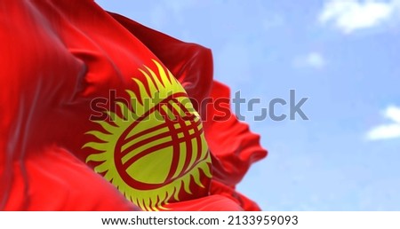 Detail of the national flag of Kyrgyzstan waving in the wind on a clear day. Kyrgyzstan is a mountainous landlocked country in Central Asia. Selective focus.