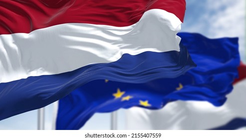 Detail of the national flag of the Netherlands waving in the wind with blurred european union flag in the background on a clear day. Democracy and politics. European country. Selective focus.