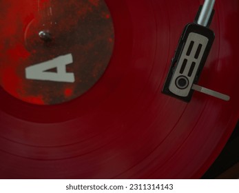 Detail of a needle on a track of a red vinyl record. Vintage turntable. - Shutterstock ID 2311314143