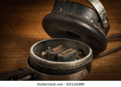 Detail of old broken vintage ear phones on a wooden table