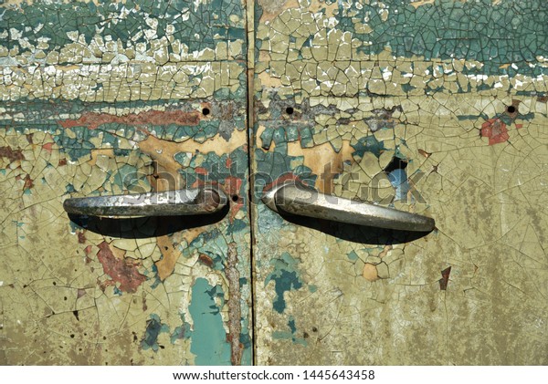 Detail of an old car door with old weathered\
paint and old door\
handles