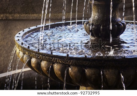 Detail of an old classic style stone fountain with flowing water