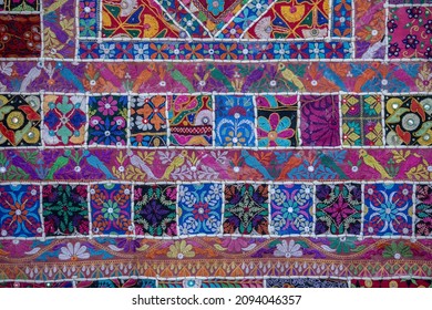 Detail old colorful patchwork carpet in background, India. Close up various textures of cloth sewn into one canvas