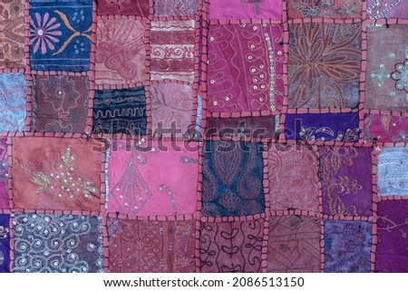 Detail old colorful patchwork carpet in background, India. Close up various textures of cloth sewn into one canvas