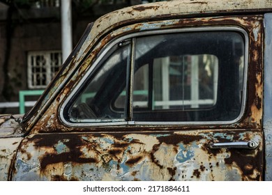 detail of old forgotten retro rusty dirty car parked in the street with damaged paint, dusty broken car, rusty wreck, abandoned vehicle, grunge background, vintage retro. side view 