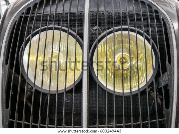 Detail of old french car with radiator grille and round\
headlight, vintage and retro background,  nostalgia for a time\
which has passed 