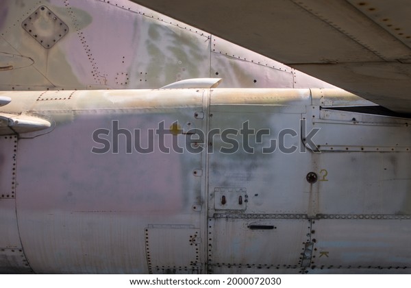 Detail of old\
grunge piece of a fighter jet with bolts, aluminum surface\
background. Light pink and green\
colours