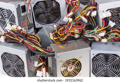 Detail of old power supply units heap as electrical background. Metal boxes stack of discarded computer hardware spare parts with fans, colorful cable bundles and white connectors. E-waste separation.