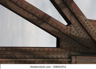 Detail Of Old Rusty Railroad Bridge With Rivets Against The Sky.