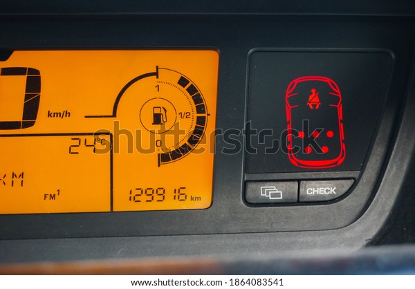 Detail on the digital dashboard of a 2010\
French-designed car, featuring a red light-signalling system\
warning of unfastened seatbelt, a gas gauge, a speedometer in\
kilometer per hour and an\
odometer