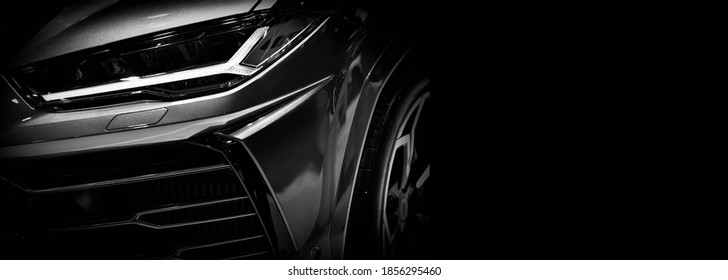 Detail on one of the LED headlights super car on black background, free space on right side for text.
