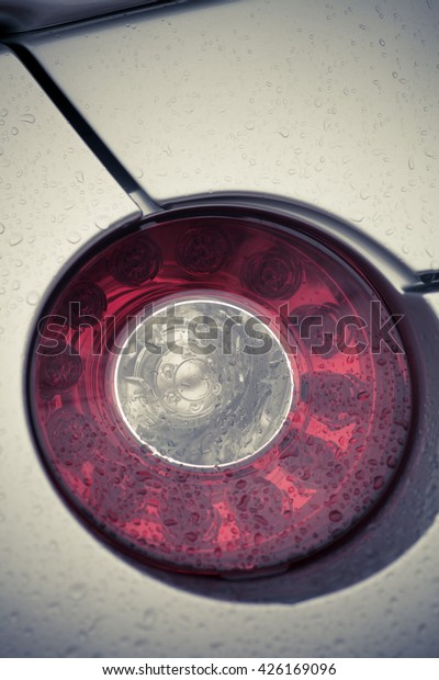 Detail on the\
rear light of a car on a rainy\
day.