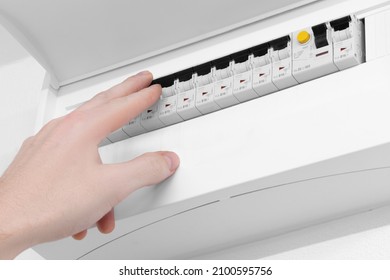 Detail Of Opened Home White Fuse Box With Set Of Black Electric Fuses. Male Hand In Position To Switch A Fuse Off. Electricity And Safety.