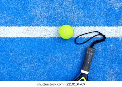 Detail of padel racket handle and bright green ball lying on blue outdoor padel court - Shutterstock ID 2210104709