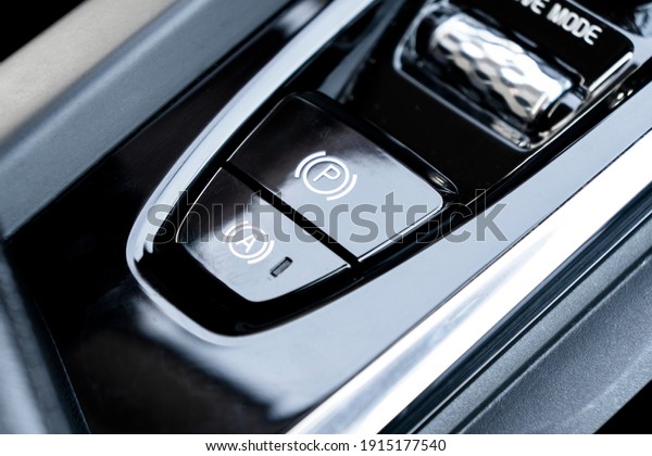 Detail of a parking\
brake in a modern car. Electronic parking brake button in a modern\
car. Button closeup.