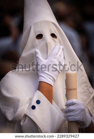 Detail penitent white holding a candle during Holy Week, Spain