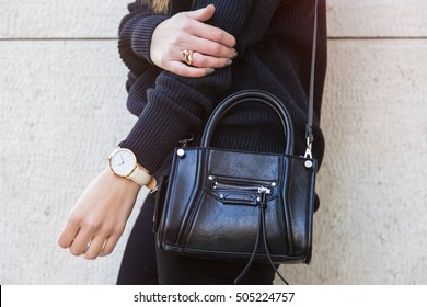 Detail Of A Perfect Fall Fashion Outfit. Fashionable Woman Wearing A Navy Blue Oversized Sweater, A White And Golden Watch And A Black Trendy Handbag, Black Jeans. 
