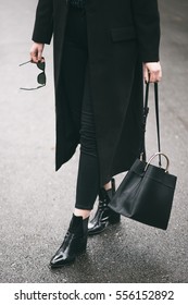 Detail Of A Perfect Fall Fashion Outfit. Fashionable Woman Wearing A Black Oversized Coat, Black Jeans, Black Ankle Shoes A Black Trendy Handbag. Fashion Blogger Outfit Details.

