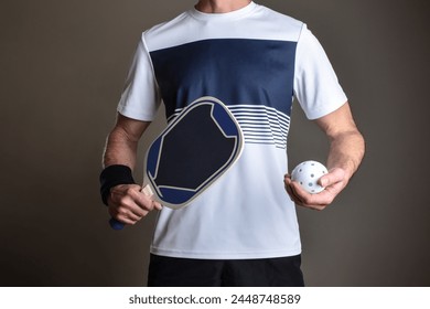 Detail of pickleball player with sports clothing and racket and playing ball in hands on gray isolated background. - Powered by Shutterstock