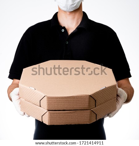 Detail of pizza boxes by deliveryman with gloves and mask. Food delivery concept.