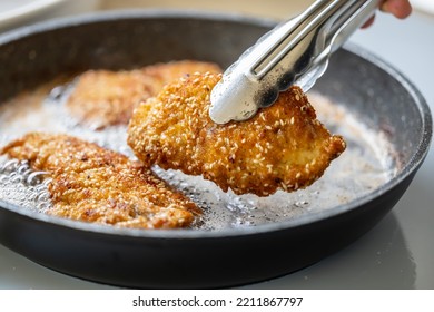 Detail Of Pliers Taking Fried Schnitzel Out Of A Sizzling Pan.