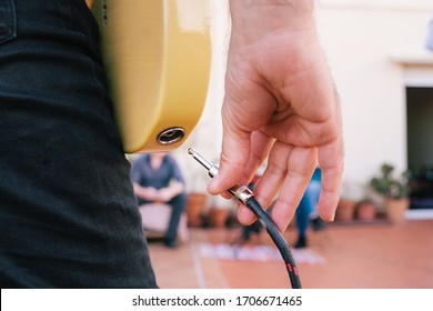 Detail of the plug into the musical instrument before an intimate concert. Close up of a male hand unplugging a music wire to an electric guitar. Leisure , free time , entertainment and music industry