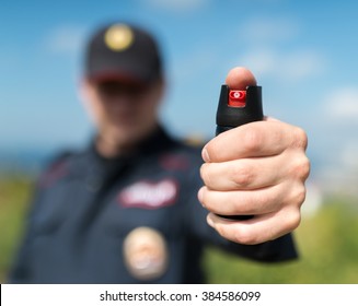 Detail of a police officer holding pepper spray. Selective focus with shallow depth of field.
