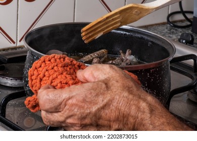 
Detail Of Pot With Game Stew, Hand Of Older Man Cooking Torcaz