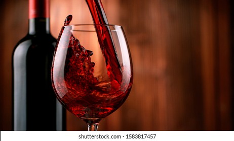 Detail of pouring red wine into glass, dark wooden background. Free space for text