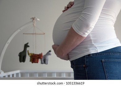 Detail Of Pregnant Woman In Front Of Baby Crib Mobile