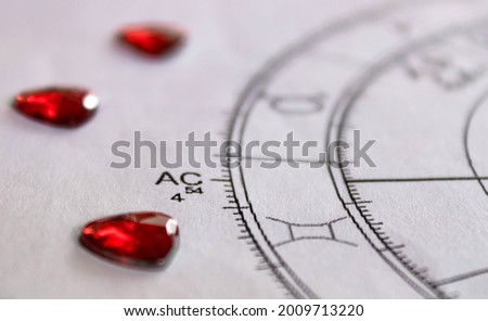 Detail of printed astrology chart with with red heart shaped sequins, ascendant sign