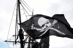 Detail Of A Real Pirate Flag With Skull And Shinbone Called Jolly Roger Fluttering In The Wind Among The Rigging Of An Ancient Wooden Pirate Ship