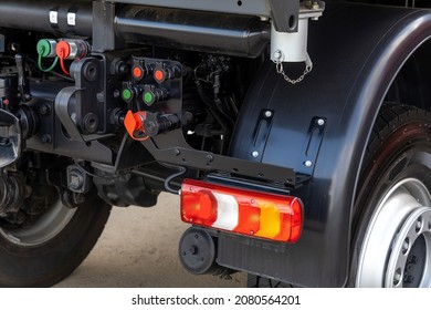 Detail Of The Rear Of A New Utility Truck. Taillights, Electrical Connectors, Plastic Mudguards, Wheels And Rims. Red Brake Lights And Orange Turn Signals. Road Safety