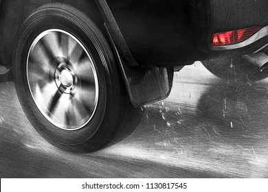 Detail of the rear wheel of a car driving in the rain on a wet road. Aquaplaning in road traffic.