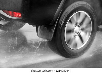 Detail Of The Rear Wheel Of A Car Driving In The Rain On A Wet Road. Aquaplaning In Road Traffic.